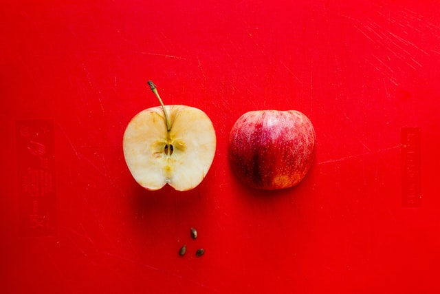 Two halves of a red apple, on the right you can see the skin, on the left you can see the inside of the apple.  Photo by Louis Hansel.